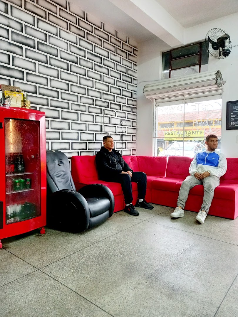 Área de espera da Barbearia Moruk com sofás vermelhos e frigobar